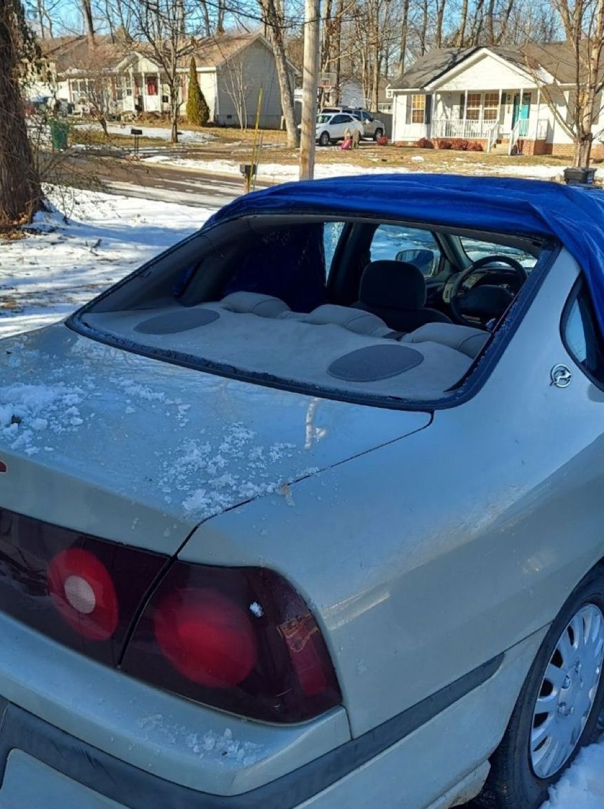 Silver car with blue roof parked in a snowy residential neighborhood