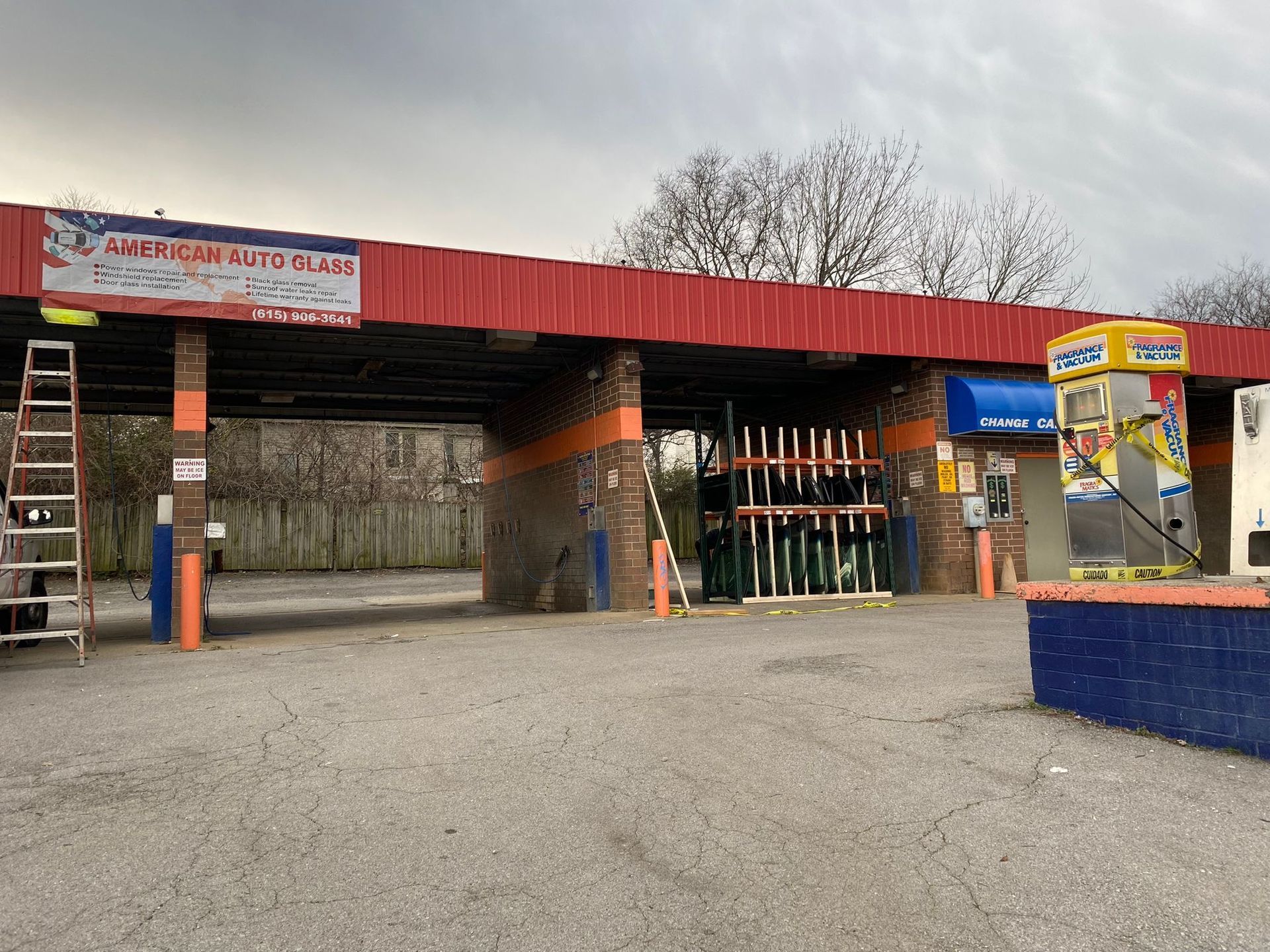 Outdoor parking lot with a red-roofed ski rental or sports shop and rows of skis under an overcast sky