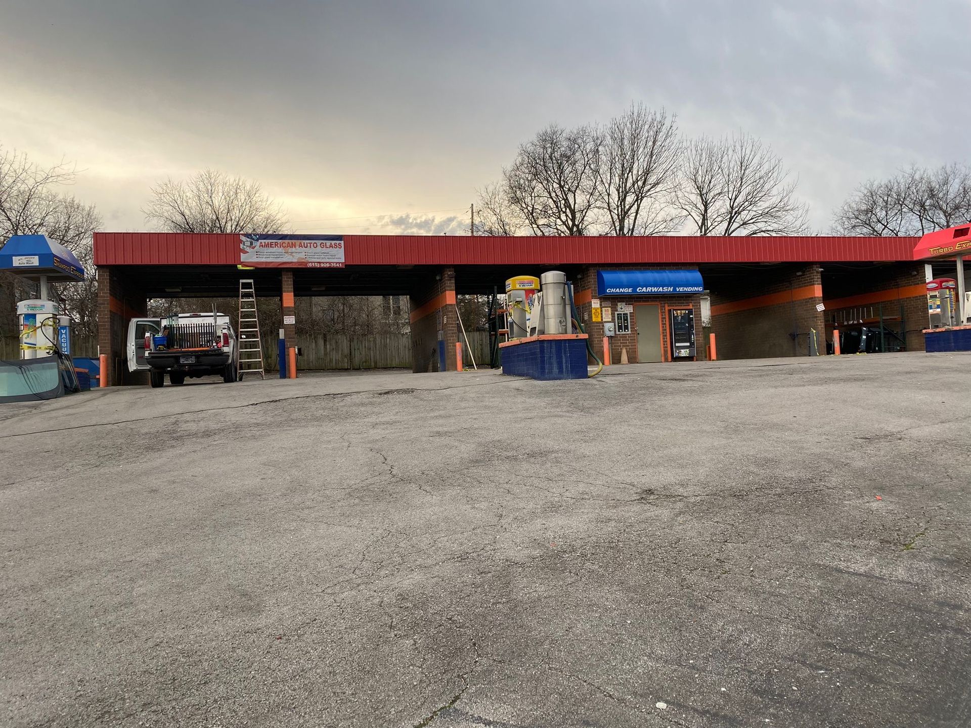 Red-roofed ticket booths at an outdoor parking lot with a few people and bare trees in the background
