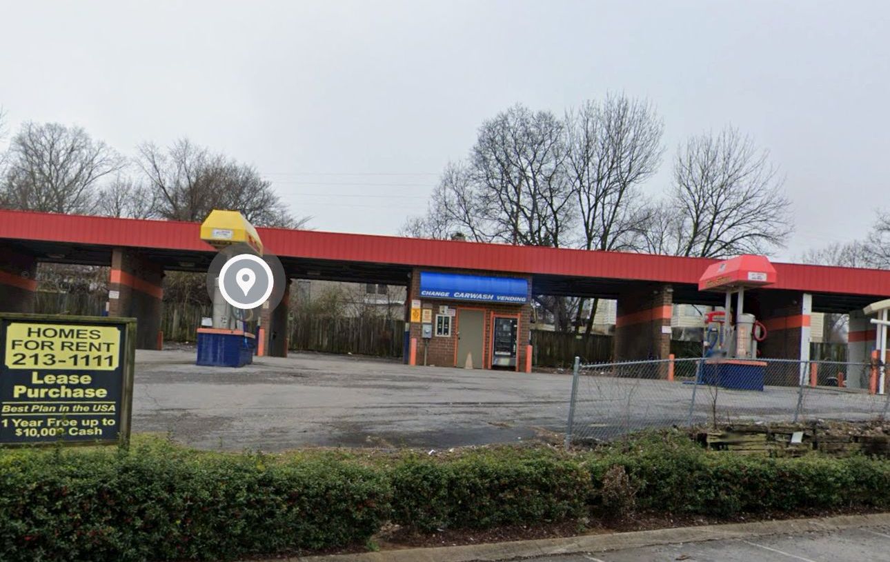 Vacant strip mall with a red roof and a parking lot, seen on an overcast day.