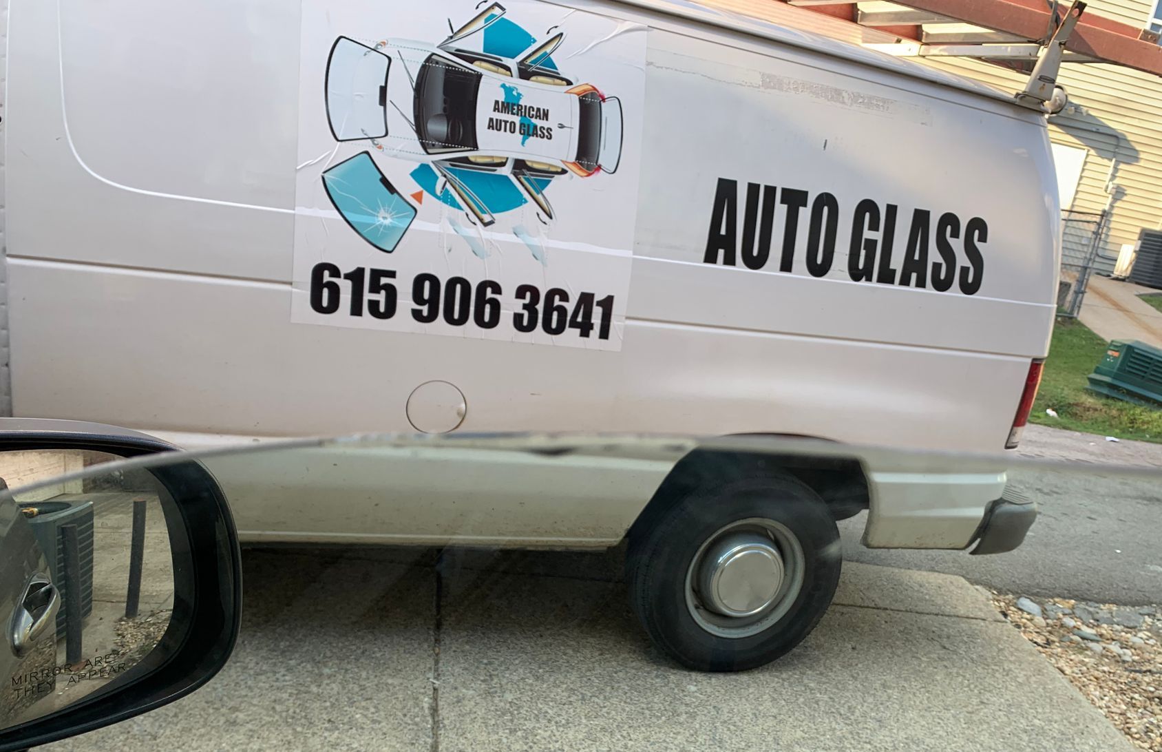 White auto glass service van with logo and phone number 615 906 3641 parked on a street