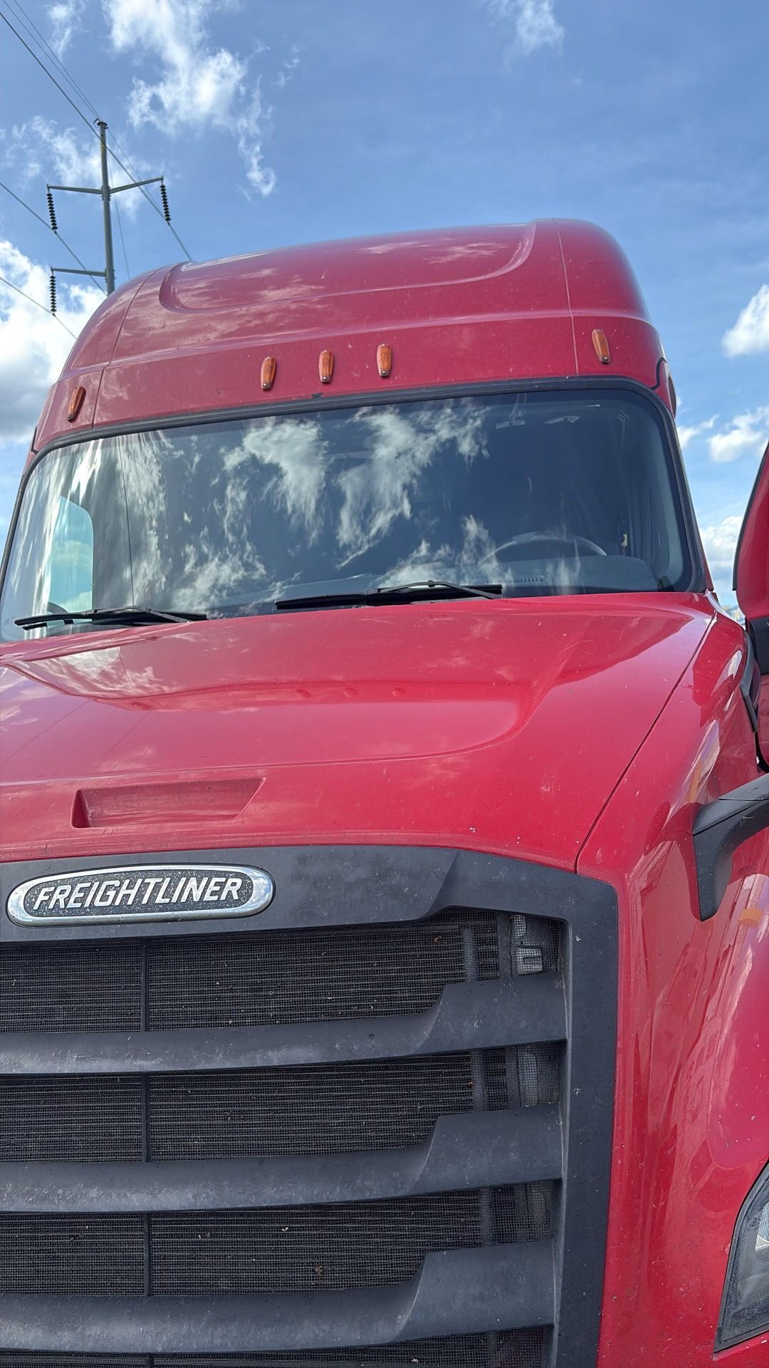 Red semi-truck cab under a blue sky, viewed from the front-left side.