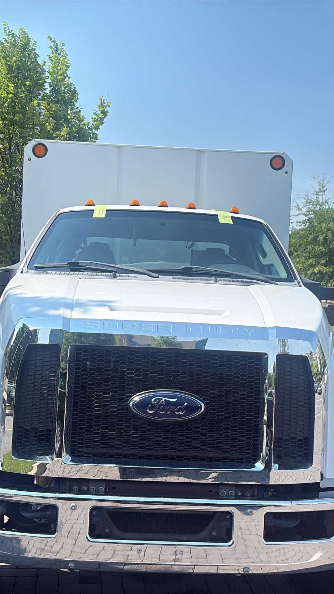 Front view of a white Ford box truck parked outdoors under a clear blue sky.